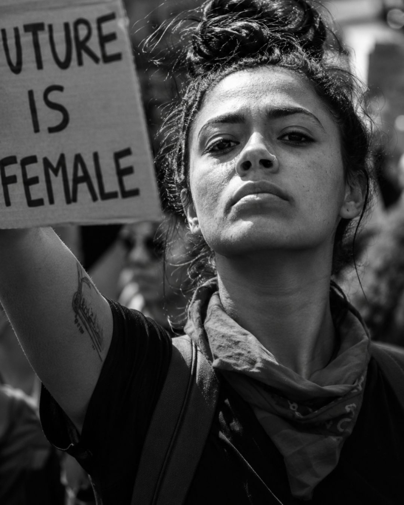 Femme déterminée en manifestation tenant une pancarte "The Future is Female" en noir et blanc, illustrant l'article sur l'hystérie comme maladie inventée pour contrôler les femmes – Hystérie Collective