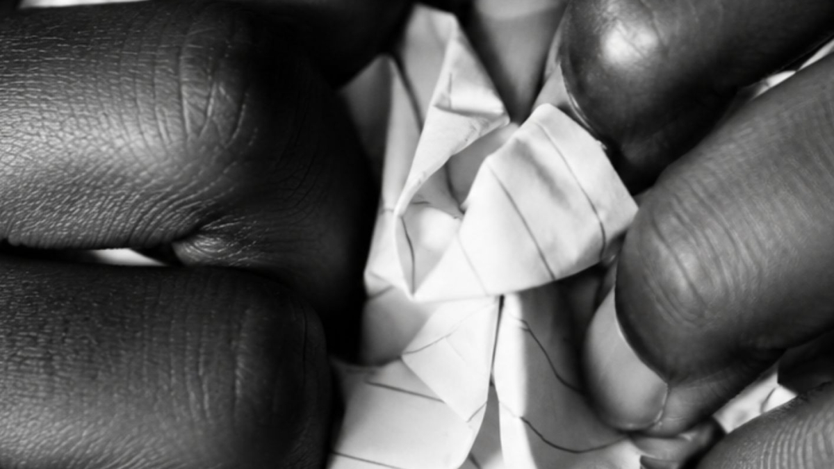 Mains froissant un papier en noir et blanc, illustrant l'article sur la liste humiliante de classement de jeunes filles créée par des hommes sur les réseaux sociaux – Hystérie Collective