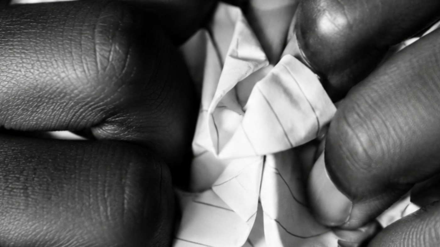 Mains froissant un papier en noir et blanc, illustrant l'article sur la liste humiliante de classement de jeunes filles créée par des hommes sur les réseaux sociaux – Hystérie Collective